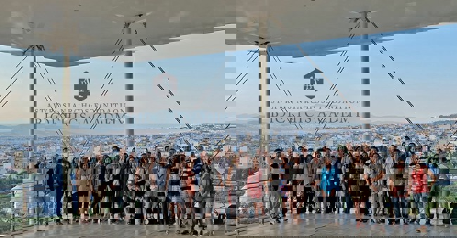 Μια μεγάλη ομάδα ποζάρει για μια φωτογραφία στο Κέντρο Πολιτισμού Ίδρυμα Σταύρος Νιάρχος, με θέα την Αθήνα 