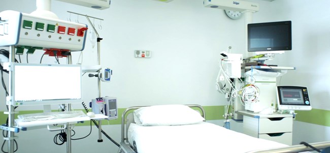 A hospital bed, monitors, and medical equipment in a hospital room